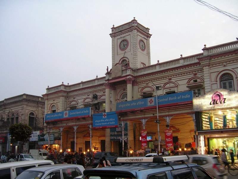 Hazratganj market with large building with cars parked in front of it.