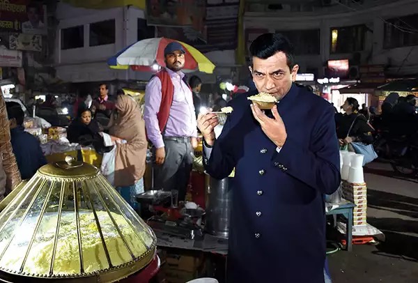 Sanjeev Kapoor, in a blue jacket is eating makhan malai at Chowk area, Lucknow.